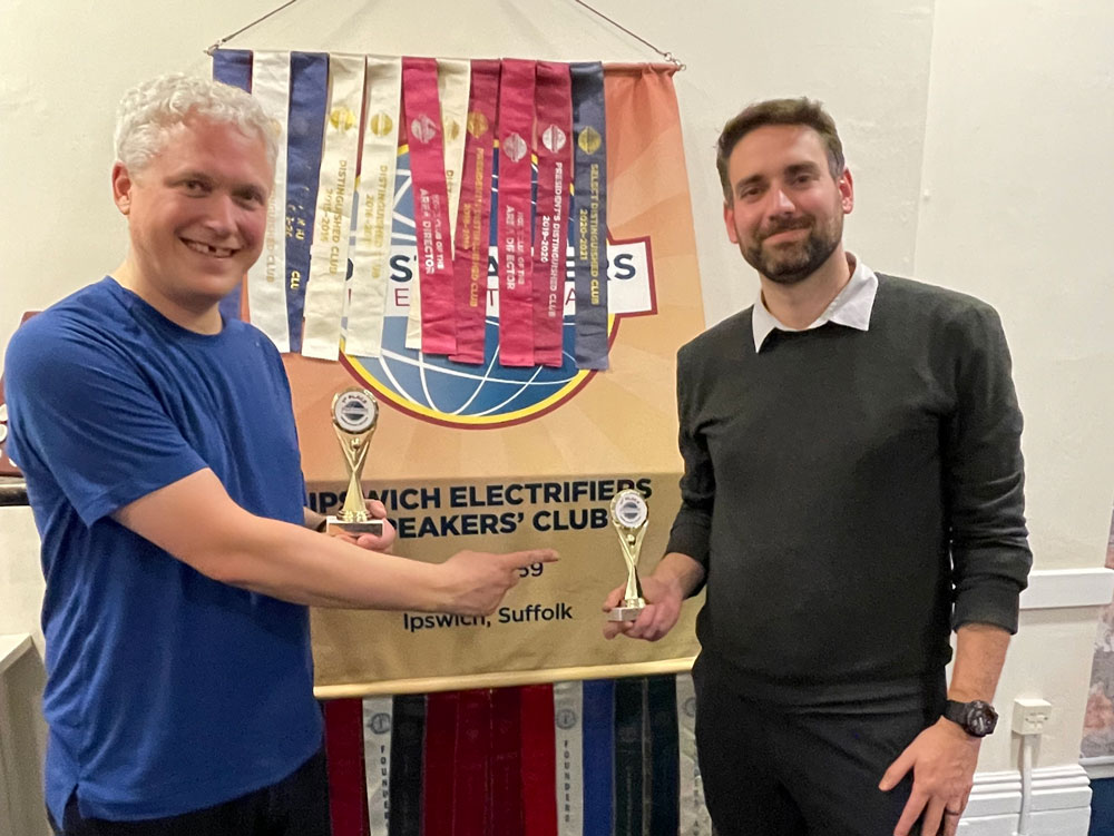 Two men shaking hands in front of a competition banner.